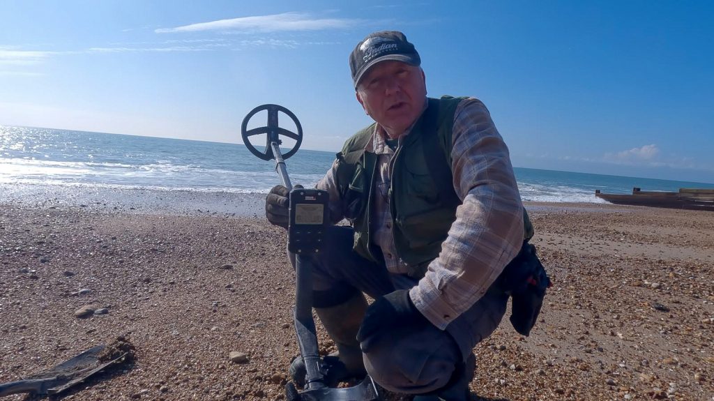 Man on the beach holding an XP metal detector